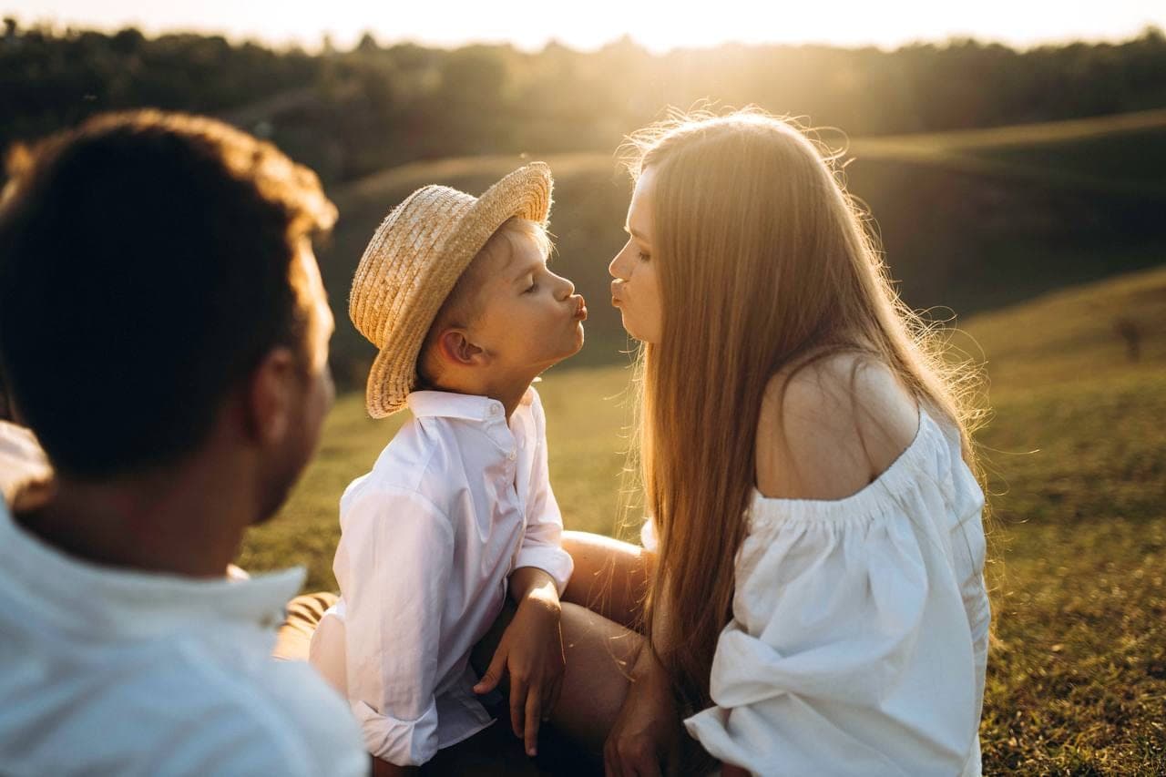 Une mère et son enfant, front contre front, au soleil couchant.
