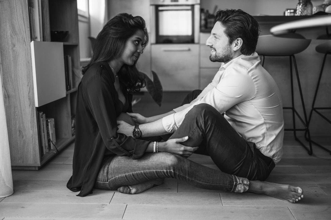 Un couple près de la fenêtre, dans l'attente, en noir et blanc.