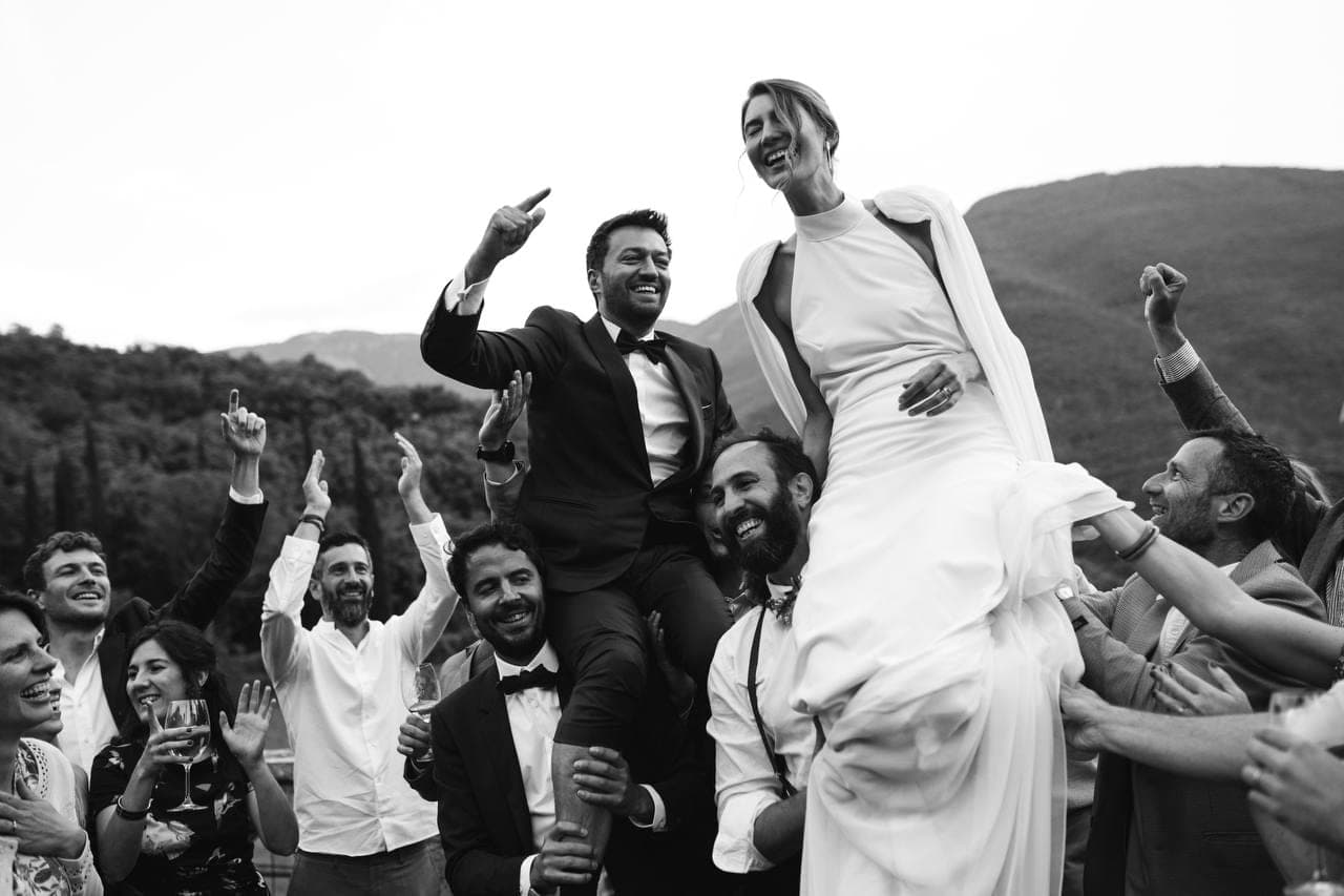 Les mariés portés par leurs invités, en noir et blanc.