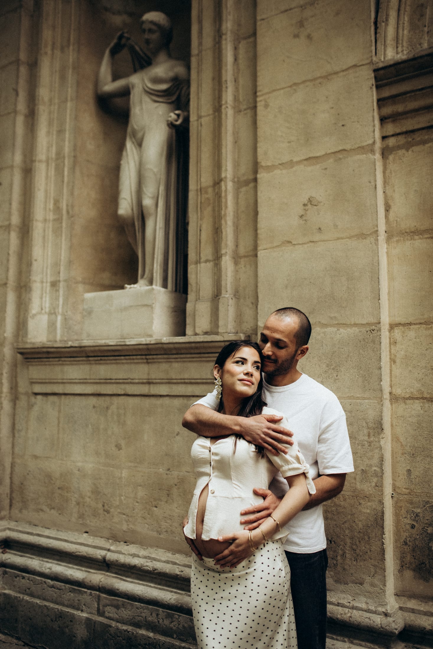A mother-to-be leaning against a stone column, in Lyon.