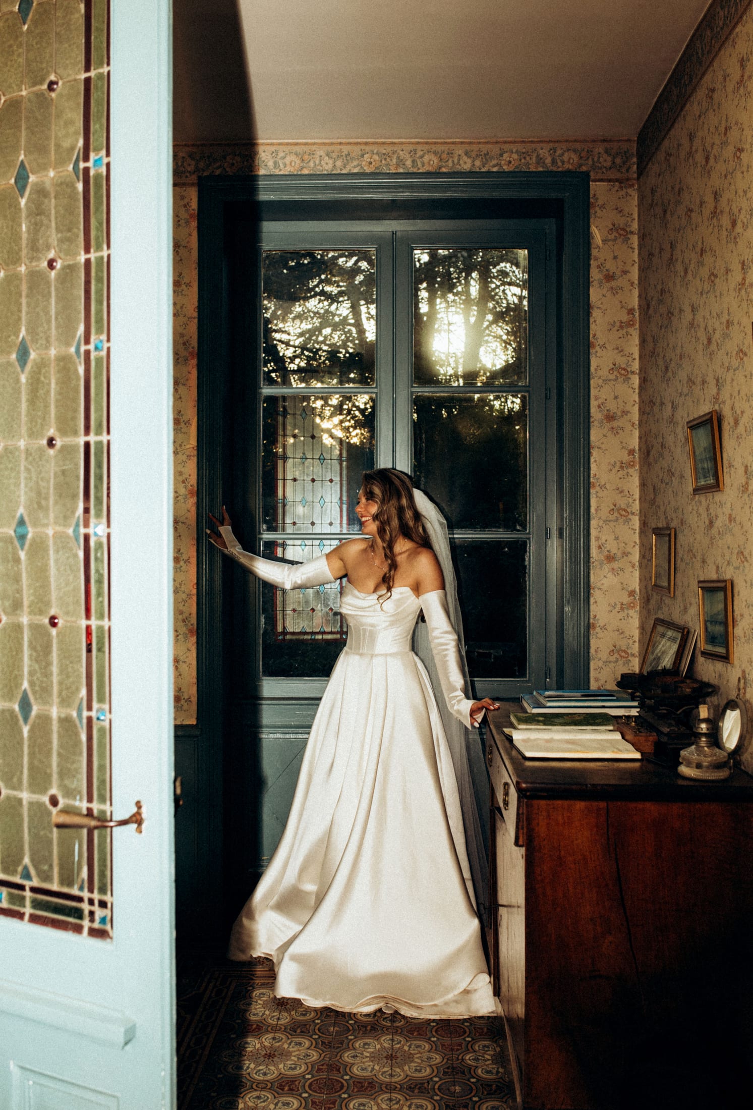 The bride getting ready, in the light of a window.